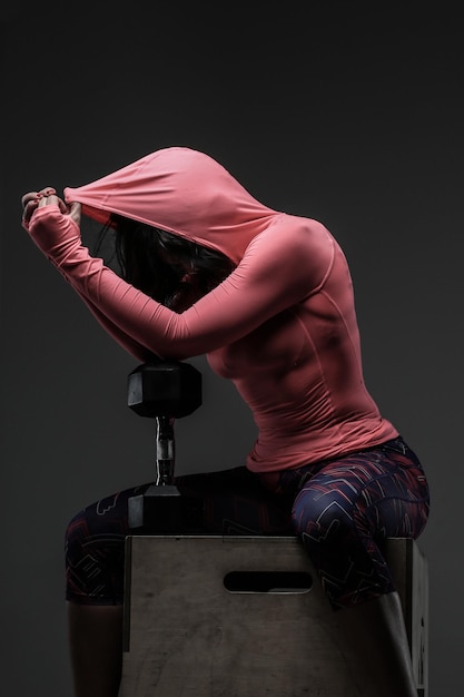 Aantrekkelijke fitness vrouw in sportkleding poseren met dumbells in sudio op grijze achtergrond