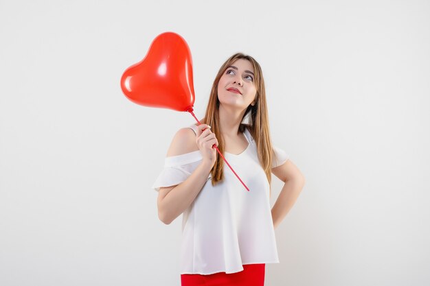 Aantrekkelijke geïsoleerde vrouw met rode hart gevormde ballon