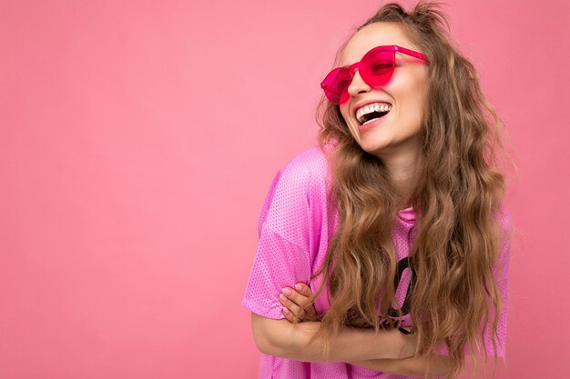 Aantrekkelijke gelukkig lachende jonge blonde vrouw die alledaagse stijlvolle kleding en moderne zonnebril draagt