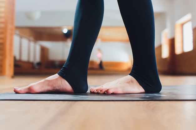 Aantrekkelijke gelukkige jonge vrouw die binnen uitwerken. mooi model doet yoga oefening op blauwe mat.