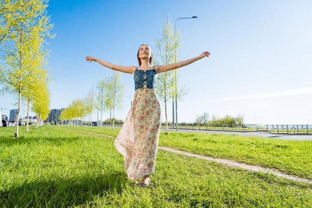 Aantrekkelijke gelukkige jonge vrouw lang gebloemde jurk vliegen haar haar genieten van gratis