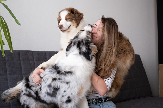 Aantrekkelijke gelukkige kus twee van de vrouwengreep Kleine schattige Australische herder blauwe merle puppy hondje.