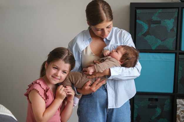 Aantrekkelijke gelukkige moeder met dochter twee. klein babymeisje op de bank. Bovenaanzicht. Gelukkig gezin. Thuis. Dol zijn op. Lief hoor. Tederheid. Grote zus.