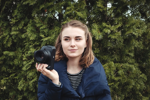 Aantrekkelijke glimlachende fotograaf die haar camera in één hand houdt