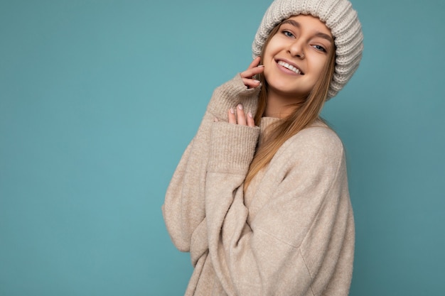 Aantrekkelijke glimlachende gelukkige jonge donkerblonde vrouw die geïsoleerd staat over een kleurrijke achtergrondmuur die alledaagse stijlvolle outfit draagt met gezichtsemoties die naar de camera kijken