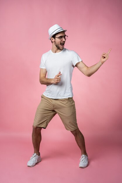 Aantrekkelijke glimlachende jonge man arm vinger tonen aan lege ruimte in gewoon kijk signaal dragen casual wit t-shirt geïsoleerd.