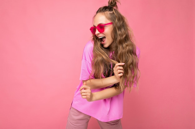 Aantrekkelijke grappige positieve blije jonge blonde vrouw, gekleed in alledaagse stijlvolle kleding en moderne zonnebril