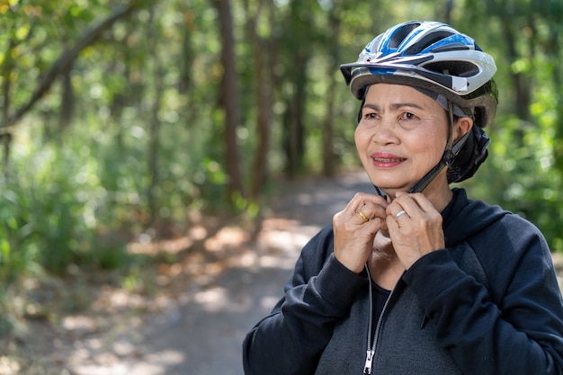 Aantrekkelijke hogere aziatische vrouw met fiets in park