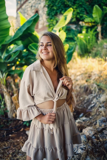 Aantrekkelijke jonge blanke vrouw staat in de buurt van bananenbomen in tropisch park