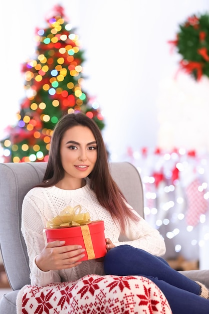 Aantrekkelijke jonge dame met geschenkdoos thuis