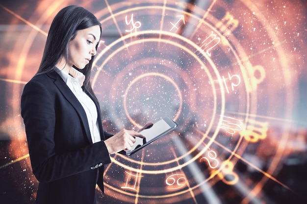 Aantrekkelijke jonge Europese zakenvrouw met behulp van tablet met creatieve sterrenbeelden hologram op onscherpe achtergrond Astrologie concept Dubbele belichting
