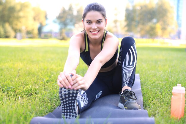 Aantrekkelijke jonge fitnessvrouw die buiten traint, rekoefeningen.