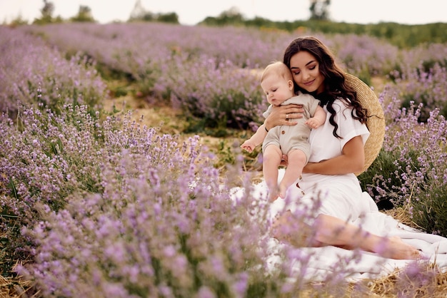 Aantrekkelijke jonge moeder speelt met haar baby in een lavendelveld