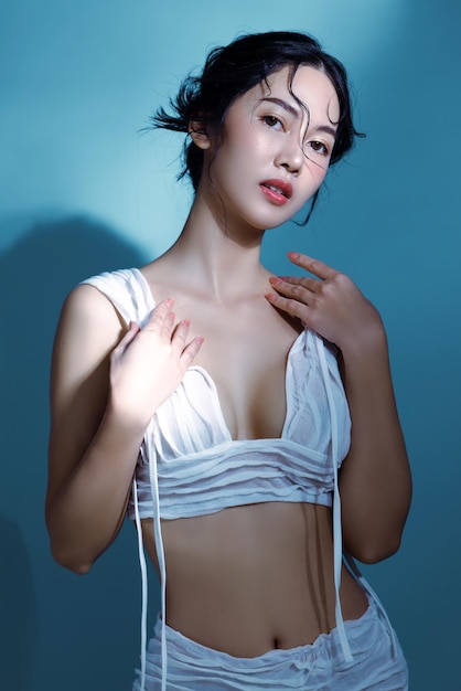 Aantrekkelijke jonge natte haren Aziatische vrouw model met perfecte frisse huid op onderwater simulatie van verlichting Gezichtsverzorging Gezichtsbehandeling Cosmetologie Plastische chirurgie Mooi meisje portret in studio
