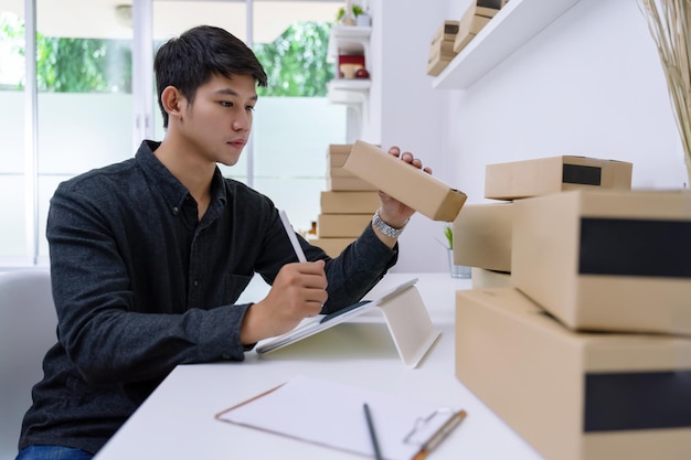 Aantrekkelijke jonge ondernemer die een pakje met producten voorbereidt om aan de klant te leveren Jonge ondernemerconcept voor online verkoop of e-commerce