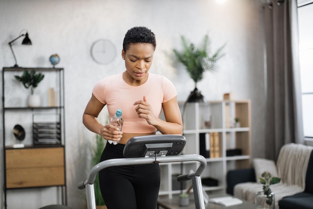 Aantrekkelijke jonge sport Afro-Amerikaanse vrouw met fles met water uit te werken