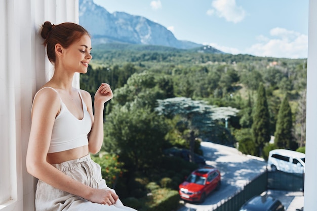 Aantrekkelijke jonge vrouw bewondert het uitzicht op de bergen op het open balkon van het hotel Lifestyle Hoge kwaliteitsfoto