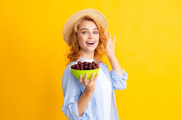 Aantrekkelijke jonge vrouw die verse kersen eet Gezonde zomervruchten Gele achtergrond Mooie vrouw poseren met een kersenmeisje met kersenpromotie