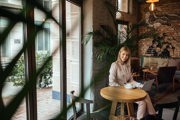 Aantrekkelijke jonge vrouw die werkt op een laptopcomputer in een coffeeshop