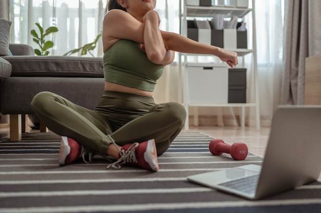 Aantrekkelijke jonge vrouw die yoga doet die yoga thuis online uitrekt Oefening binnenshuis tijdens quarantaine