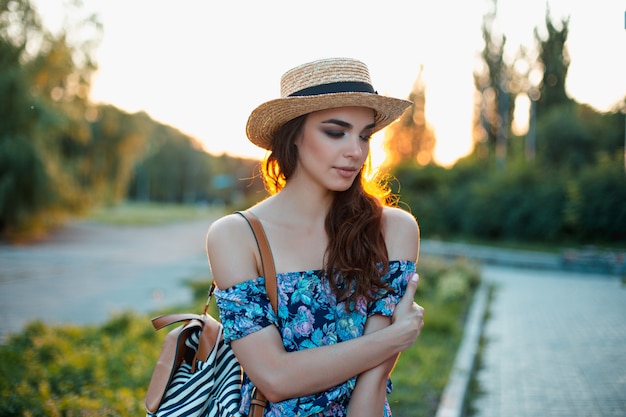 Aantrekkelijke jonge vrouw genieten van haar tijd buiten in het park met zonsondergang op de achtergrond.