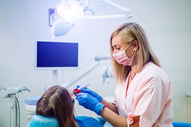 Aantrekkelijke jonge vrouw in de stomatologiekliniek met vrolijke vrouwelijke tandarts.