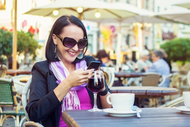 Aantrekkelijke jonge vrouw met behulp van mobiele telefoon terwijl u ontspant in café