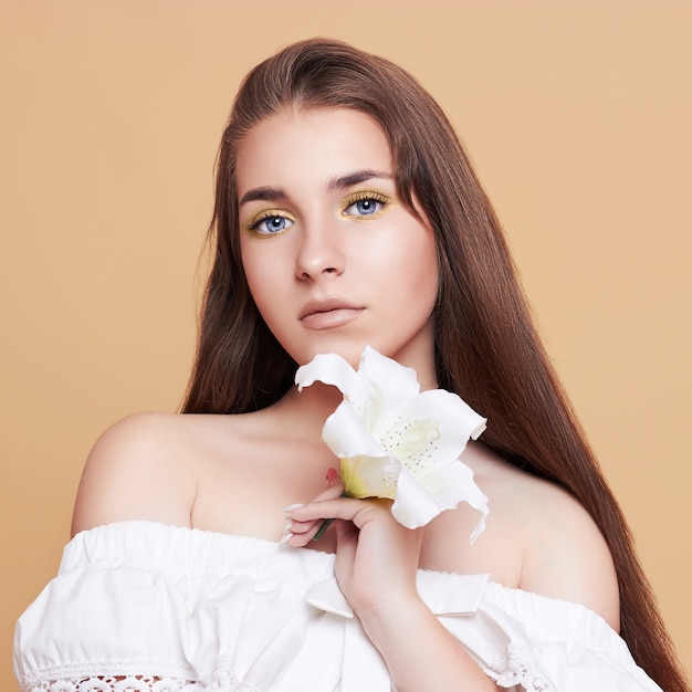 Aantrekkelijke, jonge vrouw op een witte achtergrond. Portret van een mooi meisje met een boeket witte bloemen.