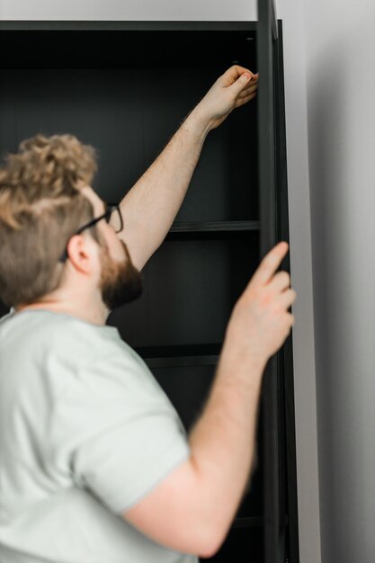 Foto aantrekkelijke jongeman assembleert meubelhandwerker en interieurobjecten concept