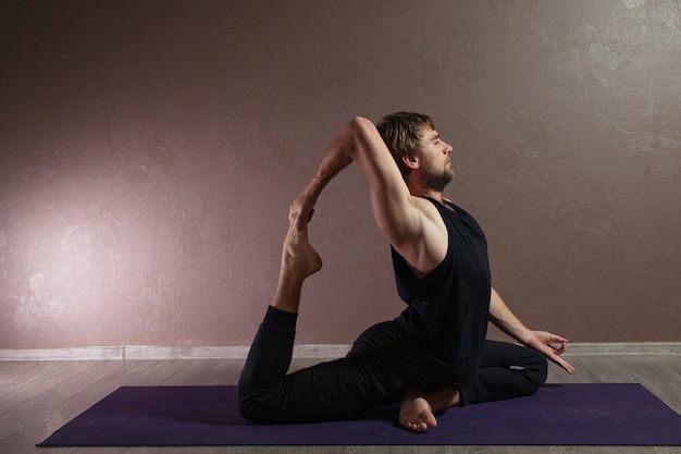 Aantrekkelijke jongeman beoefenen van yoga sportkleding dragen