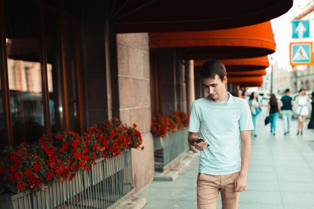 aantrekkelijke jongeman wandelen in de stad en het gebruik van smartphone