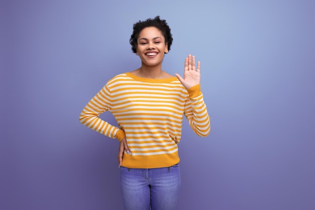 Aantrekkelijke Latijnse jonge vrouw met afrohaar in een geel gestreepte blouse