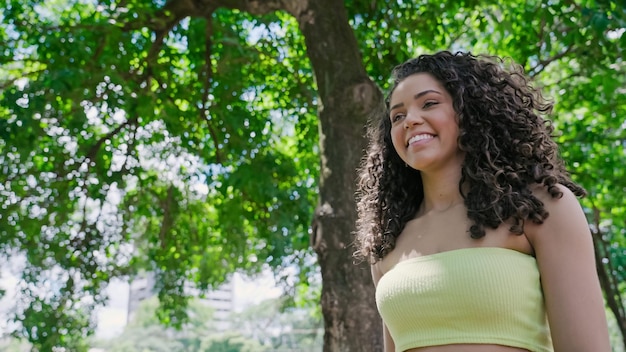 Aantrekkelijke Latijnse vrouw die op een zonnige dag in het park loopt en glimlacht.