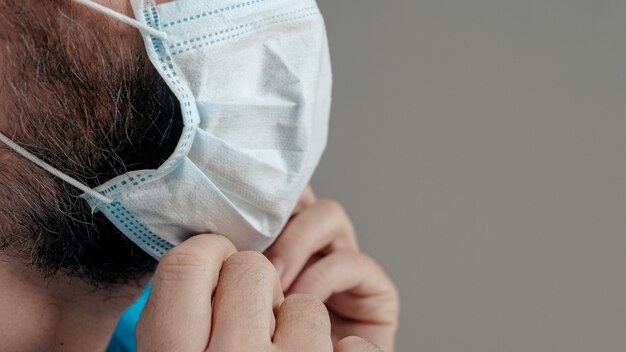 Aantrekkelijke man chirurg arts zet chirurgisch masker op zijn gezicht