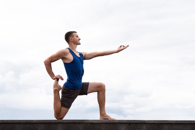 aantrekkelijke man doet yoga buiten op de hemelachtergrond