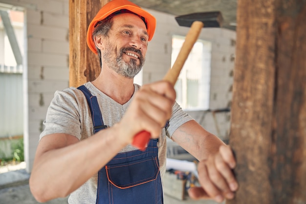 aantrekkelijke man in een helm die een spijker drijft met een hamer