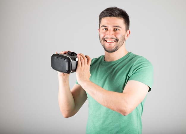 Aantrekkelijke man met behulp van virtual reality headset geïsoleerd op een grijze achtergrond