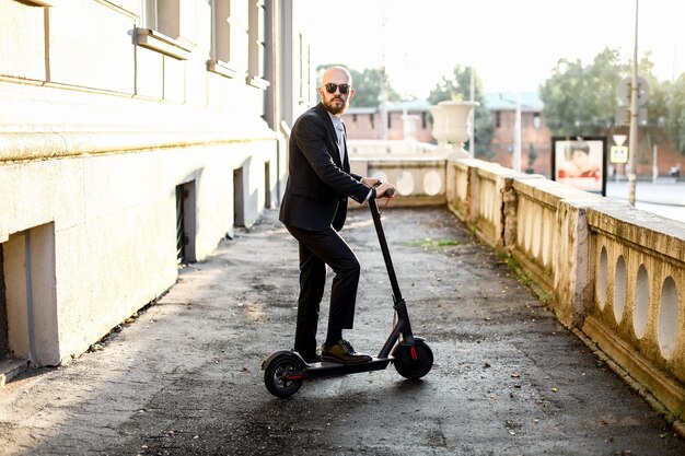 Aantrekkelijke man rijden op een kick scooter op stadsgezicht achtergrond