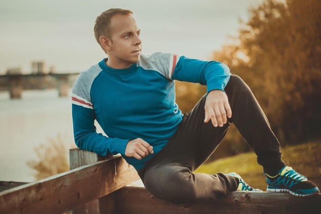 Aantrekkelijke man zittend op het strand in de avond na het sporten