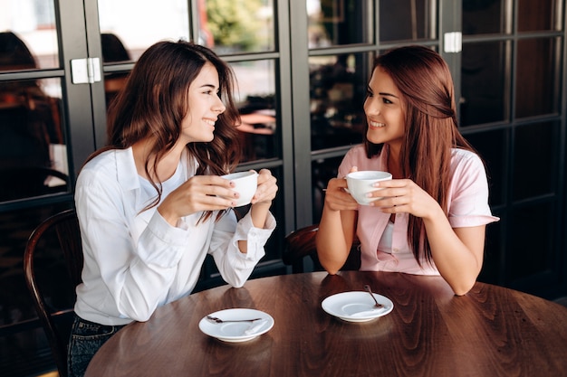 Aantrekkelijke meisjes chatten met elkaar in een zakelijk lunchcafé