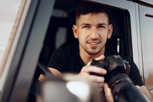 Aantrekkelijke mensenfotograaf die een foto neemt terwijl hij in zijn auto zit