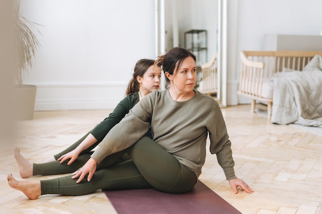 Aantrekkelijke moeder middelbare leeftijd vrouw en dochter tiener ptactice yoga samen in de lichte kamer