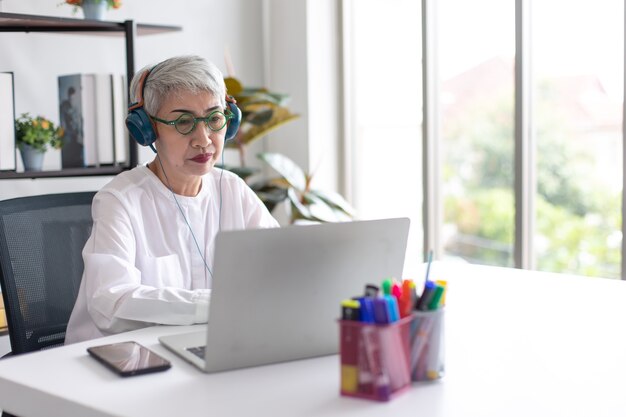 Aantrekkelijke mooie senior stijlvolle zakenvrouw met behulp van laptopcomputer voor online videoconferentie thuis
