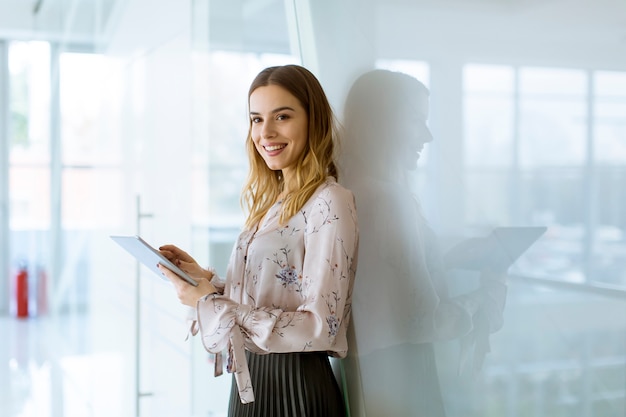 Aantrekkelijke onderneemster die een digitale tablet gebruiken terwijl status in het bureau