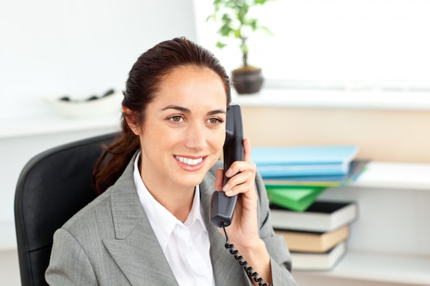 Foto aantrekkelijke onderneemster die op telefoonzitting in haar bureau spreekt