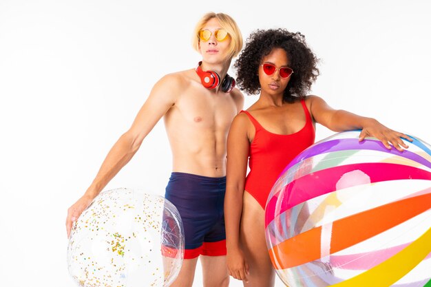 aantrekkelijke paar Europese jongen en Afrikaanse meisje in zwemkleding met zonnebril en koptelefoon naar het strand zwemmen op matrassen zwemmen