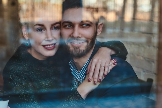 Aantrekkelijke paar romantische mensen zitten in café en kijken door het raam.