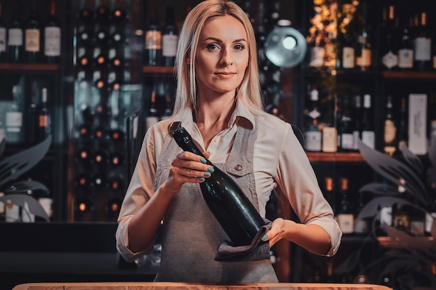 Aantrekkelijke peinzende vrouw bereidt wijn voor sommelier om het bij wijnboetiek te specialiseren.