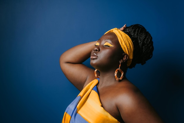 Foto aantrekkelijke plus grootte afrikaanse vrouw met traditionele afrikaanse kleding en sieraden aanrakende haar