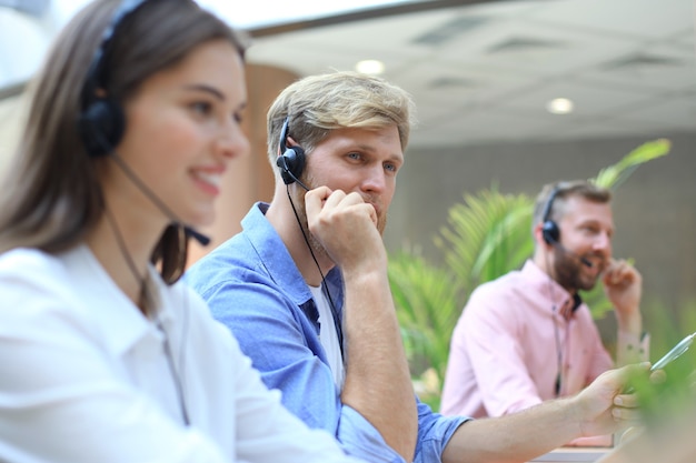 Aantrekkelijke positieve jonge ondernemers en collega's in een callcenterkantoor.